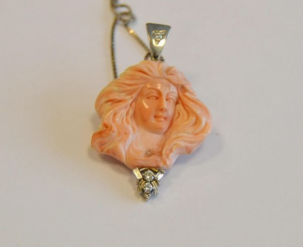        Collana in oro bianco, diamanti e corallo ,  ad un filo  con ciondolo in corallo inciso a busto di donna e tre brillanti                                                                  