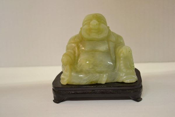  Intaglio Cina sec. XX,  in giadeite ragfigurante il Buddha ridente alt. cm 10 ca, poggiante su base in legno