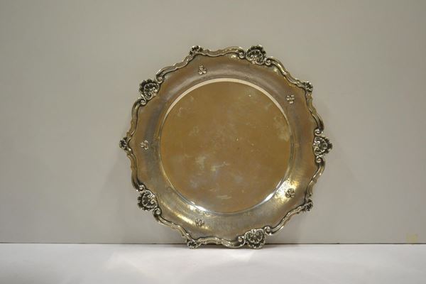  Piatto  in argento con tesa decorata da conchiglie e volute, g 864, diam. cm 34