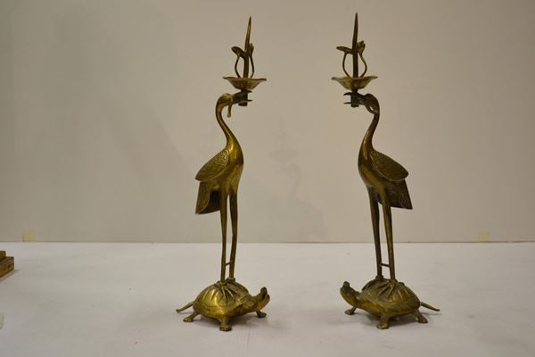  Coppia di candelieri in metallo a forma di gru, Cina o Giappone, inizi XX secolo , i due uccelli poggianti le lunghe zampe sul dorso di due tartarughe, nel becco  i candelieri a forma di fiore di loto   alt.                          