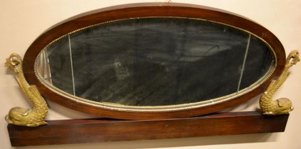  Specchio, Toscana, periodo Impero,  in noce, di forma ovale fiancheggiato da due delfini in legno intagliato e dorato, cm 57x120