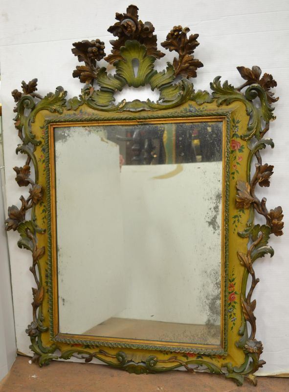  Specchiera  in stile veneto del Settecento, in legno intagliato, dorato e dipinto nei toni del verde, alta cimasa traforata con decorazione di fiori e frutta, girali e tralci di vite ricadenti ai lati, cornice rettangolare decorata a tortiglione, cm 122x95&nbsp;&nbsp;&nbsp;&nbsp;&nbsp;&nbsp;&nbsp;&nbsp;