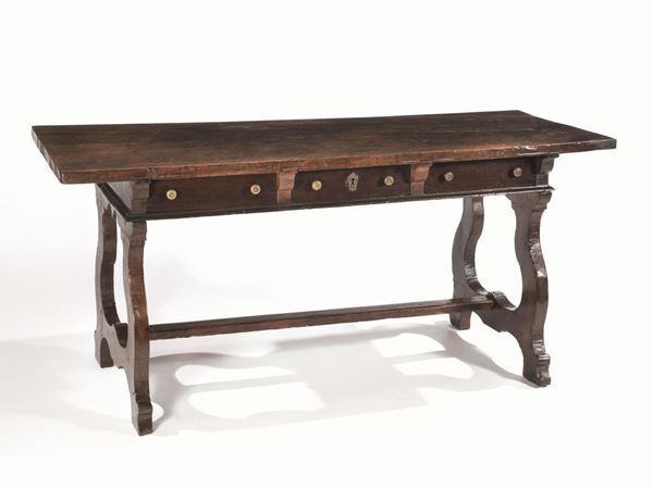   Tavolo, Emilia, met&agrave; sec. XVII , in noce a patina scura, piano rettangolare realizzato da un'unica tavola, tre cassetti nella fascia, gambe a lira&nbsp;riunite da traversa, cm 179x70x83, alcuni restauri e sostituzioni &nbsp;&nbsp;&nbsp;&nbsp;&nbsp;&nbsp;&nbsp;&nbsp;&nbsp;