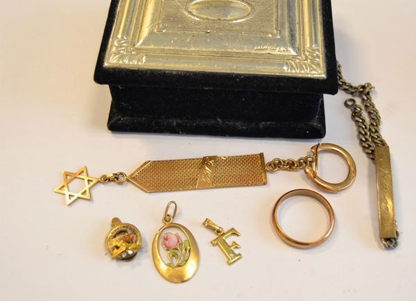   Fede in oro  , g 5,6   Portachiavi in oro giallo  con ciondolo a forma di stella di David , g 16,7   Pendente in oro giallo e smalto , e  Spillo  da bavero in oro , g 4,8   Pendente in oro   a forma di lettera F, g 0,7   Braccialetto in argento  con scritta Marco , g 10,7   Scatolina portagioie  in velluto e argento (6) 