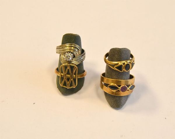   Anello in oro e diamante  con fascia scanalata intrecciata ,al centro brillante , di circa ct, 0,18    Anello in oro giallo , zaffiri e rubini  a fascia alta traforata e decorata con rubino e zaffiri    Anello in oro giallo e zaffiri  con fascia decorata con zaffiri   Anello in oro giallo  realizzato come uno scudo .  Complessivi g 12 (4) 