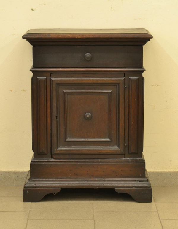                  Credenzino, inizi sec. XX,  in noce a patina scura, ad uno sportello ed un cassetto, cm 62x32x74, parzialmente ricostruito con materiale antico         - Asta Gioielli, argenti, modernariato, mobili e dipinti - Poggio Bracciolini Casa d'Aste