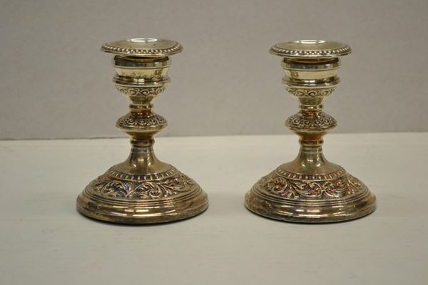 Coppia di candelieri, in metallo argentato decorati da volute, alt. cm 12,5