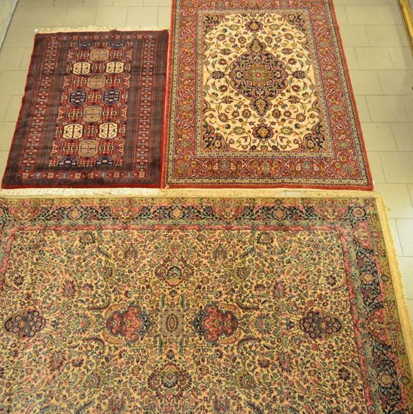 Tre tappeti, sec. XX, fondi multicolori a motivi geometrici e             