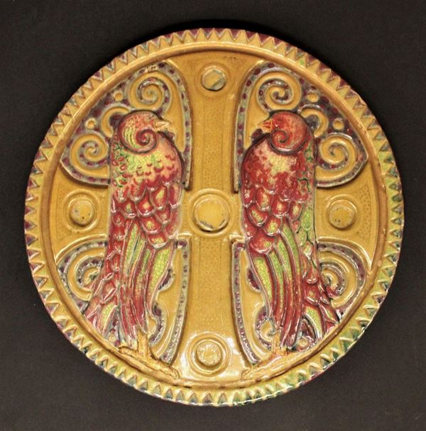 Formella circolare, inizi XX, manifattura Chini, in ceramica decorata a rilievo in policromia raffigurante coppia di pappagalli, diam. cm 29,5