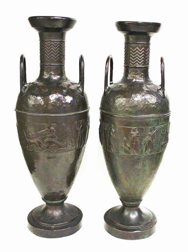 Coppia di anfore biansate, inizi sec. XX, in rame sbalzato, fascia centrale a motivo figurato arcaizzante, piede circolare, su una delle due dedica &#8220;all&#8217; Onorevole Arturo Luzzatto, il Consiglio dell&#8217; Industria Vetraria Toscana, ( Marconi Norton ) 8 aprile 1908&quot;, alt. cm 75