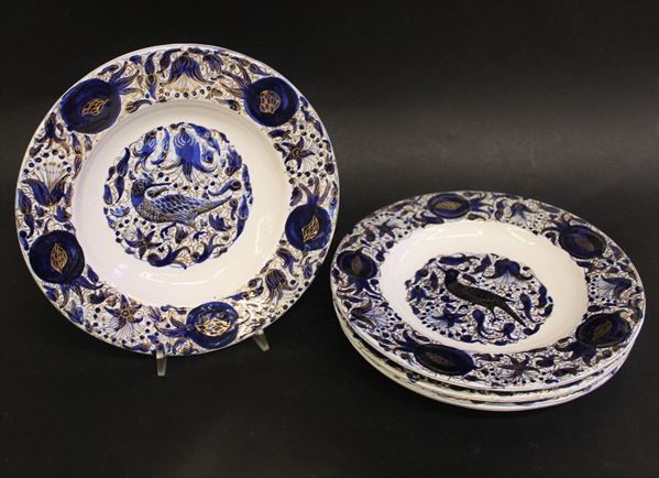 Quattro piatti, Faenza, inizi sec. XX, manifattura Melandri, in maiolica decorata nei toni del blu e lumeggiato in oro sulla tesa e nel cavetto, diam. cm 24 (4)