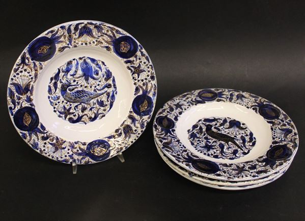 Quattro piatti, Faenza, inizi sec. XX, manifattura Melandri, in maiolica decorata nei toni del blu e lumeggiato in oro sulla tesa e nel cavetto, diam. cm 24 (4)  - Asta GIOIELLI, ARREDI D'ANTIQUARIATO, E DIPINTI DAL XVI AL XX SECOLO - Poggio Bracciolini Casa d'Aste