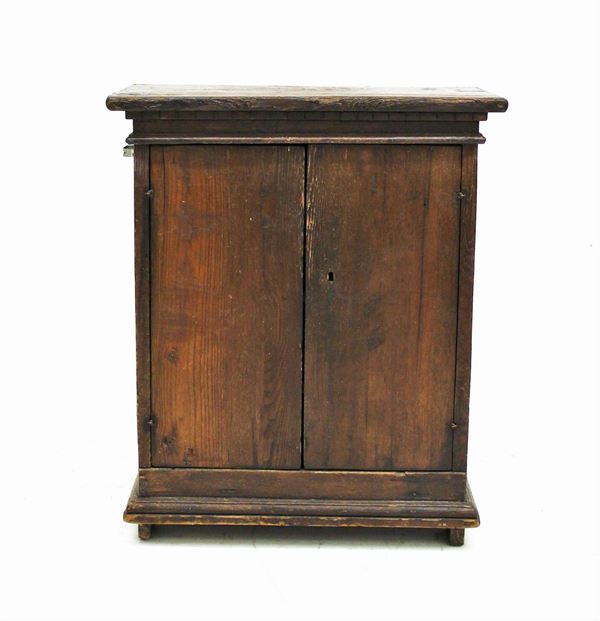 Stipo, sec. XIX, in castagno, piano rettangolare sotteso da modanatura a dentelli, due sportelli, fianchi lisci, cm 75,5x39,5x89,5, difetti