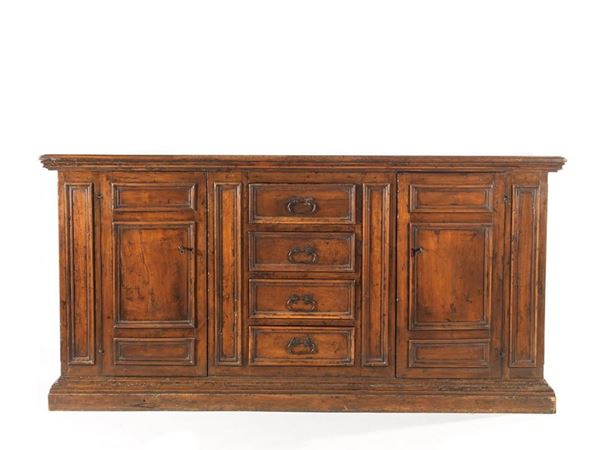 Credenza, Italia centrale, in stile 600, in noce, piano rettangolare a becco di civetta, fronte ornato da sformellature e scandito da lesene a inquadrare al centro quattro cassetti e ai lati due sportelli, fianchi sformellati, cm 107x216x58, costruito con materiale antico