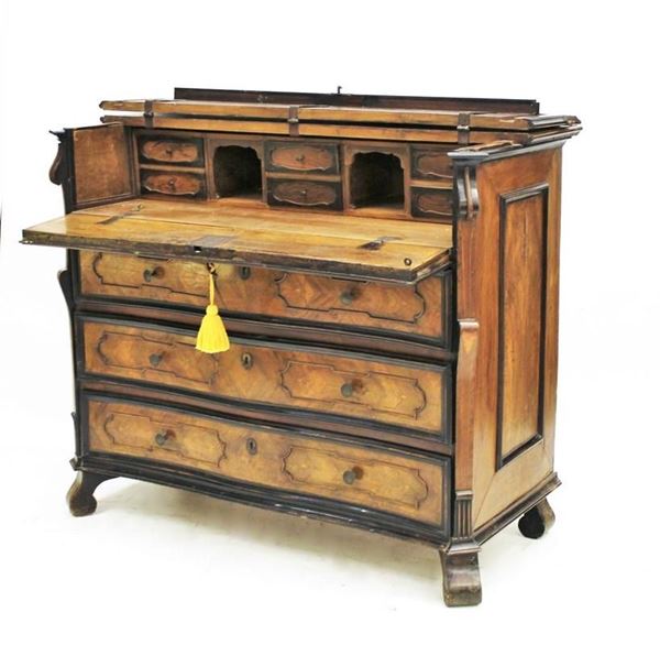 Cassettone, Lombardia, sec. XVIII, lastronato in noce e radica di noce, filettato in acero, piano incernierato, finto cassetto a calatoia celante vano a giorno e tiretti, sotteso da tre cassetti dal fronte mosso a riserve mistilinee a profili nervati ebanizzati, lesene laterali aggettanti e modanate, piedi a ricciolo, cm 145x67x115 difetti, modifiche e restauri