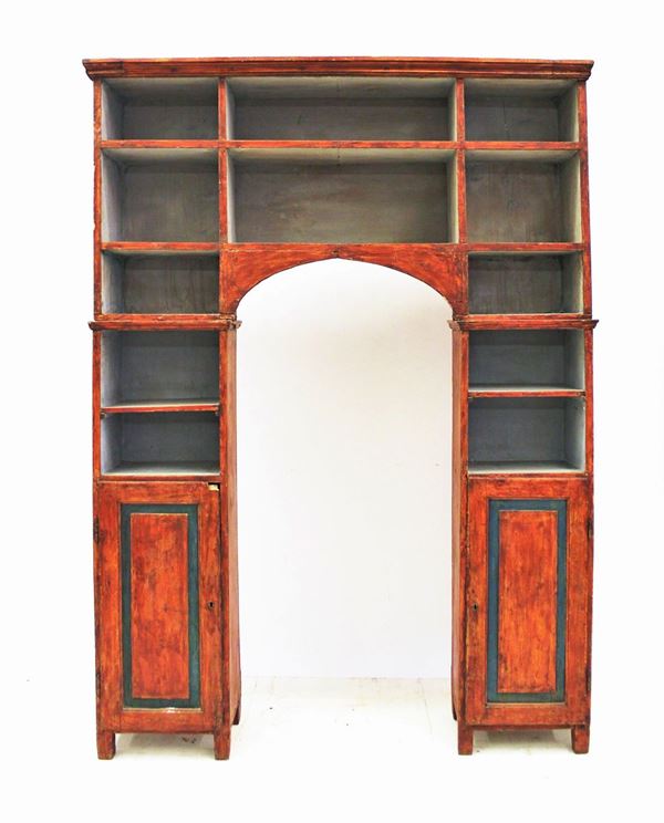 Libreria a ponte, sec. XIX, in legno laccato nei toni del rosso e del grigio, scaffali a giorno e coppia di sportelli al basamento dei due montanti,