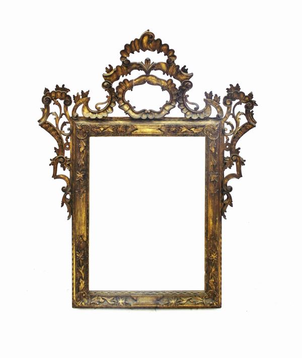 Specchiera, in stile 700, in legno intagliato e dorato, luce rettangolare, cimasa riccamente intagliata a volute contrapposte centrate da motivo rocaille, cm 114,5x146