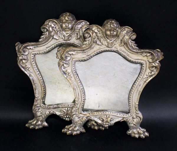 Coppia di Cartagloria, sec. XVII, in legno intaglaito e argentato a mecca, luce sagomata percorso da motivo perlinato, cimasa centrata da cherubino tra volute ingentilite da motivi fitoformi, piedi ferini, cm 36,5x29