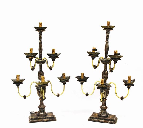 Coppia di candelabri, in stile 700, in legno argentato, fusto tornito ad elementi vasiformi ed intagliato a motivi fogliati su cui si innestano cinque bracci metallici a volute desinenti in bobeches in tole, alt. cm 85, elettrificati, difetti (2)