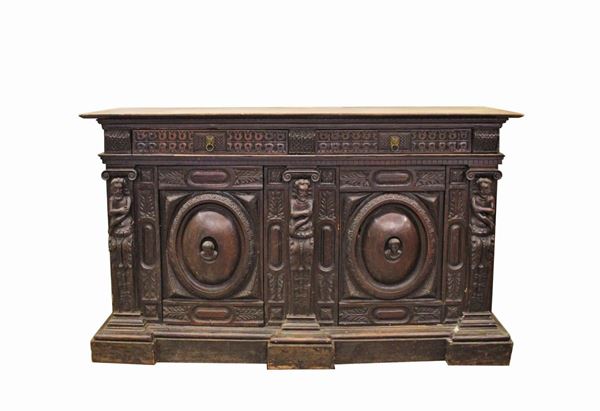 Credenza, Francia, sec. XIX, in noce, piano rettangolare sotteso da due cassetti allineati, due sportelli, clipeati centrati da volti scolpiti, scanditi da cariatidi, piede a fascia continua dalla linea spezzata, cm 189x57,5x109