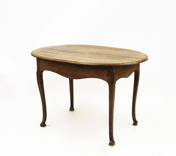 Tavolino, sec. XVIII, in noce, piano ovale a becco di civetta, grembialina sagomata, gambe mosse desinenti in zoccolo, cm 118x77x74, difetti