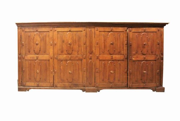 Grande armadio, in stile 600, in quercia, quattro sportelli specchiati decorati a riserve mistilinee in noce, cimasa rettilinea aggettante, piede a mensola, cm 420x68x192