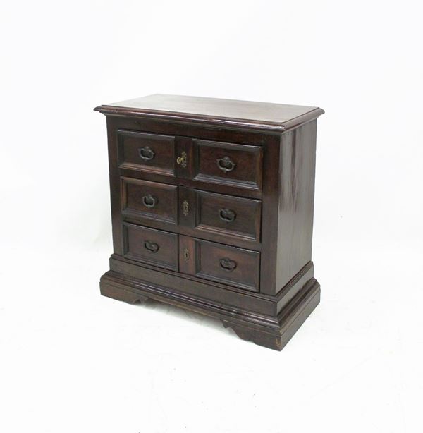 Piccolo cassettone, sec. XVII, in noce, piano rettangolare a becco di civetta, fronte a tre cassetti doppia a riserva rettilinea nervata, fianchi lisci, piedi a mensola, cm 90x47x81, modifiche