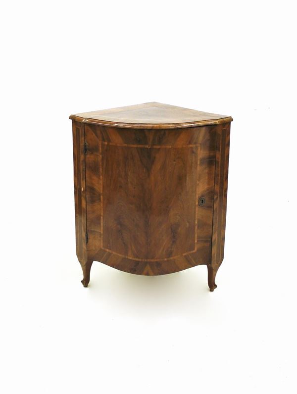 Angoliera, sec. XVIII, lastronata e filettata in noce, piano sagomato dal profilo convesso profilato in legno di testa, fronte ad uno sportello sagomato, gambe mosse, cm 67x54,5x90