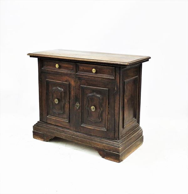 Credenza, Piemonte, sec. XVIII, in noce, piano a becco di civetta sotteso da motivo a dentelli incavi, fronte a due cassetti allineati, due sportelli intagliati a riserve rettilinee centrate da specchiatura mistilinee, fianchi specchiati, piede  a mensola, cm 120x55x96, modifiche