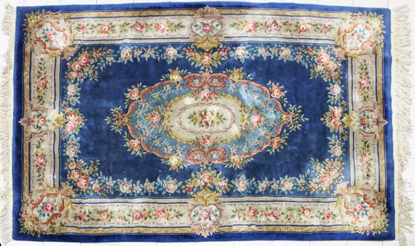 Tappeto savonnerie, manifattura europea, sec. XX, campo nei toni dell&#8217;azzurro, fascia di bordura e medaglione centrale nei toni del panna decorati serti fioriti, cm 213x305