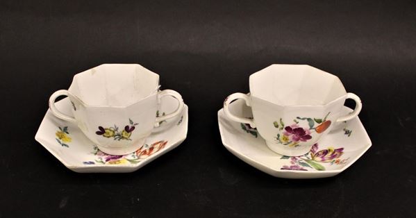 Coppia di tazze biansate e piattini biansate, Meissen 1745, di forma ottagonale in porcellana bianca dipinta a composizioni floreali policrome, marca spade incrociate in blu, restauri