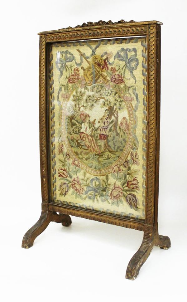 Parascintille, fine sec. XIX, in legno intagliato e dorato, pannello ricamato a piccolo punto raffigurante scena di genere, cm 51x32x87