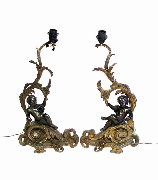 Coppia di sculture, fine sec. XIX, in bronzo patinato e dorato, raffiguranti coppia di putti adagiati su ramages fogliati, adattati a lumi, completi di paralume, alt. cm 56 (2)