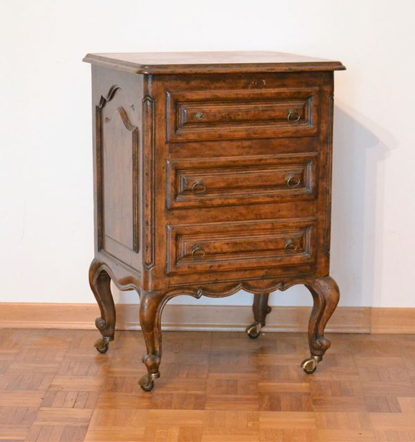Comodino, in stile provenzale del 700, in noce, piano rettangolare, fronte a tre cassetti, grembialina centinata, piedi mossi su rotelle, segreto,&nbsp; cm 51x41x75