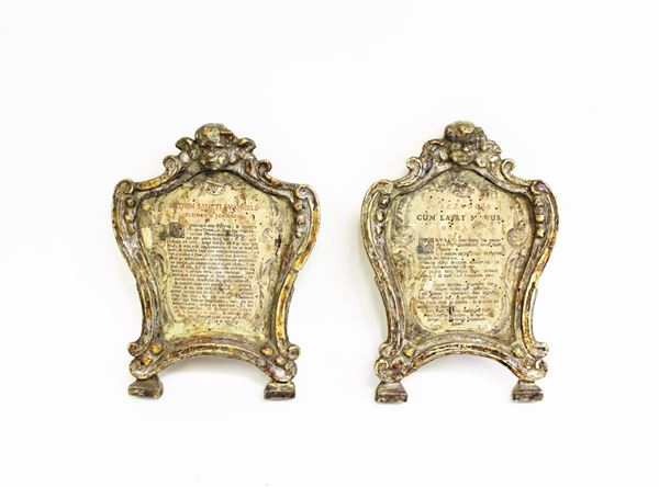 Coppia di cartaglorie, sec. XVIII, in legno intagliato e scolpito e argentato, luce sagomata, cimasa centrata da cherubino tra volute contrapposte, cm 26,5x19