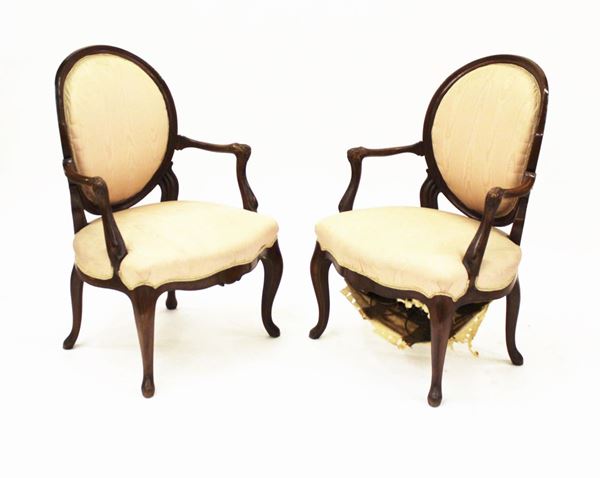 Coppia di poltroncine, in stile 700, in noce, rivestite in stoffa nei toni del rosa, schienale dalla linea ovale, braccioli a giorno, fascia modanata, gambe mosse, alt. cm 95