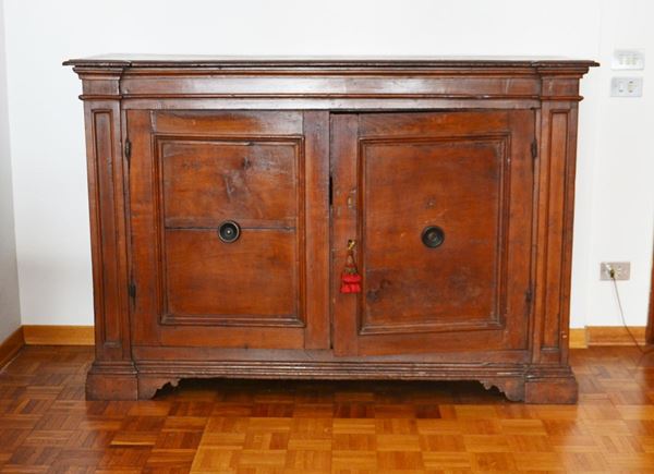 Credenza, sec. XVIII, in noce, due sportelli specchiati tra tra paraste aggettanti, piedi a mensola sagomati, cm 153x54x101