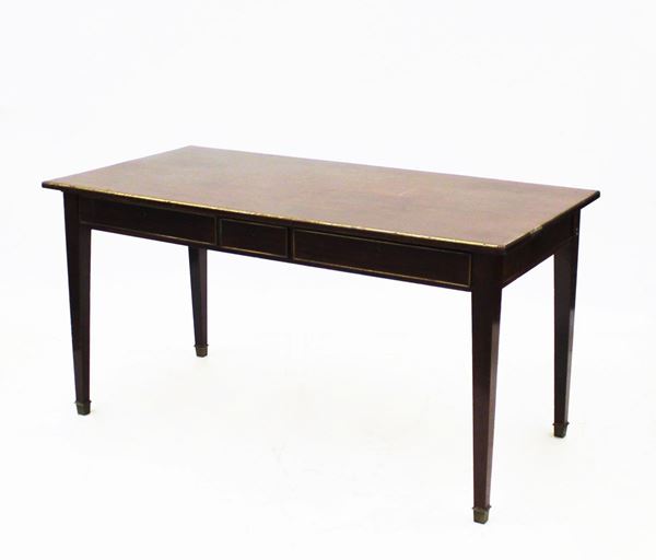 Scrivania, Inghilterra, inizi sec. XX, in mogano, piano rettangolare profilato in bronzo sotteso da tre cassetti allineati nella fascia, gambe troncopiramidali desinenti in sabot bronzeo, cm 179x74x76