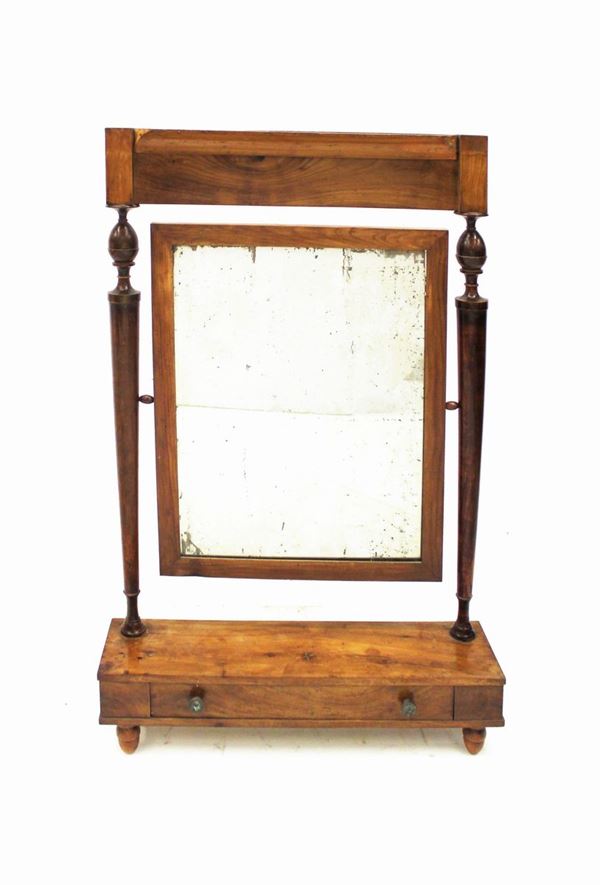 Specchiera da appoggio basculante, sec. XIX, in noce, specchio rettangolare tra montanti torniti ad elementi vasiformi, poggianti su pedana ad un cassetto a tutta lunghezza su piedi torniti, cm 72x19x113, difetti