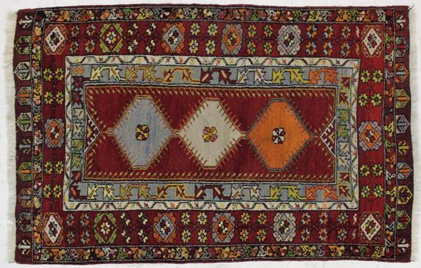 Tappeto, Anatolia, sec. XX, impianto geometrico su campo rosso, tre medaglioni centrali, cm 172,5x110