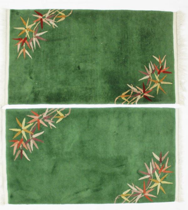 Coppia di tappeti, Cina, sec. XX a campo libero nei toni del verde decorati in due cantonali a motivi fogliati a guisa di bamb&ugrave;, cm 150x90