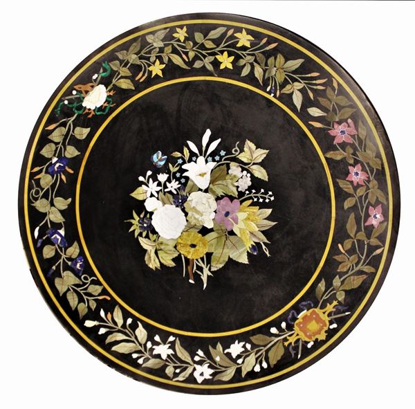 Piano di tavolo circolare, sec. XX, in commesso di pietre dure, fondo in marmo nero del Belgio commesso con malachite, lapislazzuli, serpentino, calcedonio, quarzo&nbsp; e marmi policromi, diam. cm 120 (difetti)