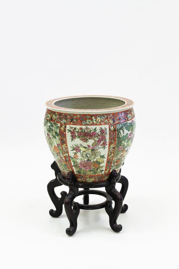 Grande vasca da pesci, Cina, sec. XX, in porcellana dipinta in policromia ad ampie riserve motivi florofaunistici, interno decorato a motivi ittici, su base in legno, diam. cm 52,5 alt. cm 75,5