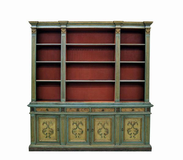 Libreria a doppio corpo, sec. XX, in legno laccato dipinto in policromia e lumeggiato in oro, corpo superiore tripartito scandito da lesene triglifate desidenti in capitelli, corpo inferiore a quattro cassetti allineati sottesi da sportelli, piede a fascia continua, cm 250x47x255