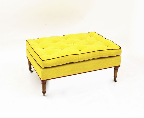 Pouff, inizi sec. XX, seduta rettangolare con imbottitura capitonn&eacute;, rivestito in stoffa gialla e finiture rosse, quattro gambe lignee tornite desinenti in rotelle metalliche, cm 108x72x51