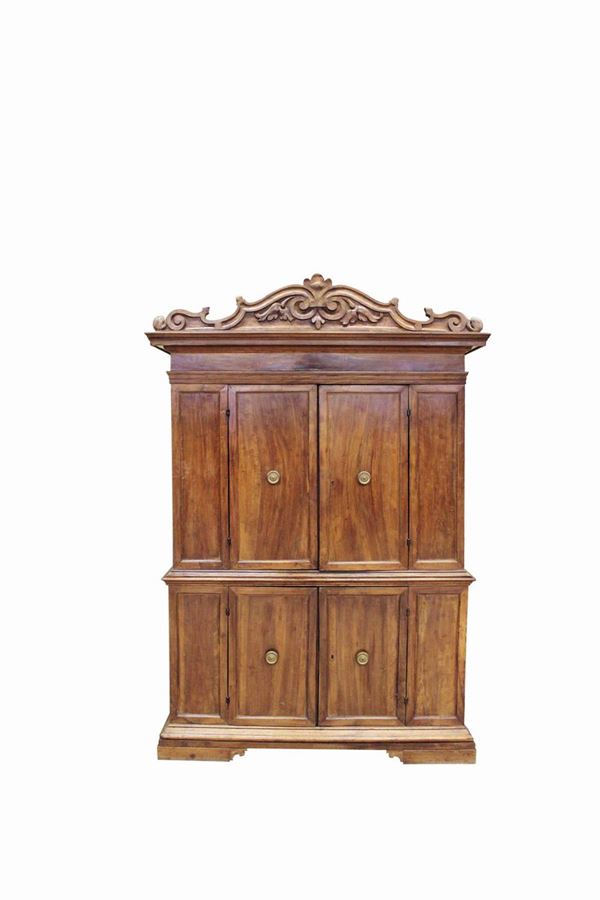 Mobile a doppio corpo, sec. XVII, in legno di noce, fronte a due coppie di sportelli disposti su due livelli, cimasa riccamente scolpita e sagomata a volute contrapposte, piede a mensola, cm 158x60x230, restauri