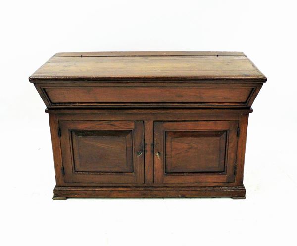 Madia, sec. XIX, in castagno, fronte svasato, piano rettangolare incernierato, due sportelli specchiati, piedi a mensola, cm 133x64x83