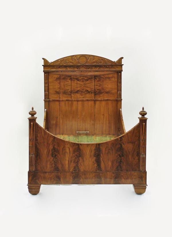 Letto, Carlo X, inizio sec. XIX, in legno lastronato in ciliegio, testiera a cimasa curvilinea intagliata a cigni affrontati desinenti in motivo a rosetta e palmette centrati da ghirlanda, doppio ordine di modanature a baccellatura e embricature, erme solpite a guisa di cingi, motivo che si ripresenta sulla pediera a profilo incavo come i montanti, cm 158x218x188
