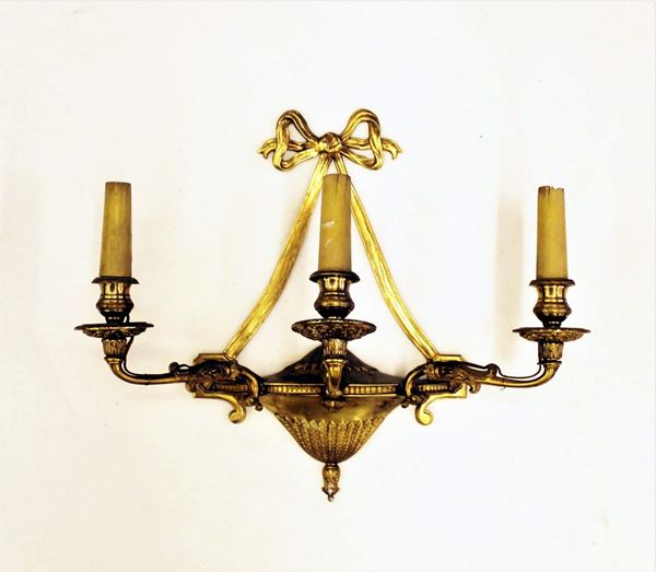 Applique, sec. XX, in bronzo dorato e cesellato, corpo a paniera da cui si dipartono tre braccia mossi desinenti in punto luce, cm 35