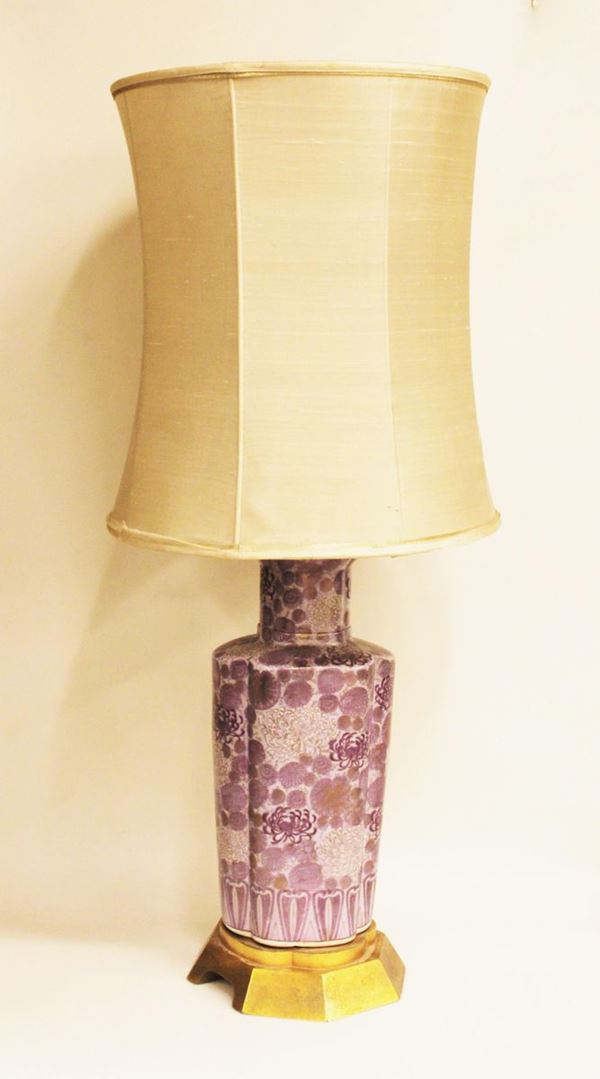 Lume da tavolo, sec. XX, realizzato con vaso orientale in ceramica dipinta nei toni del viola a motivi floreali, su base in legno dorato, completa di paralume, alt. cm 54